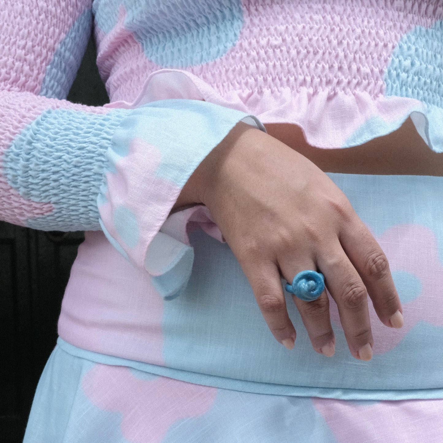 Torso y brazo de modelo pluszize de tes morena usando top y falda en colores celeste y morado y anillo Merengón Mora Azul