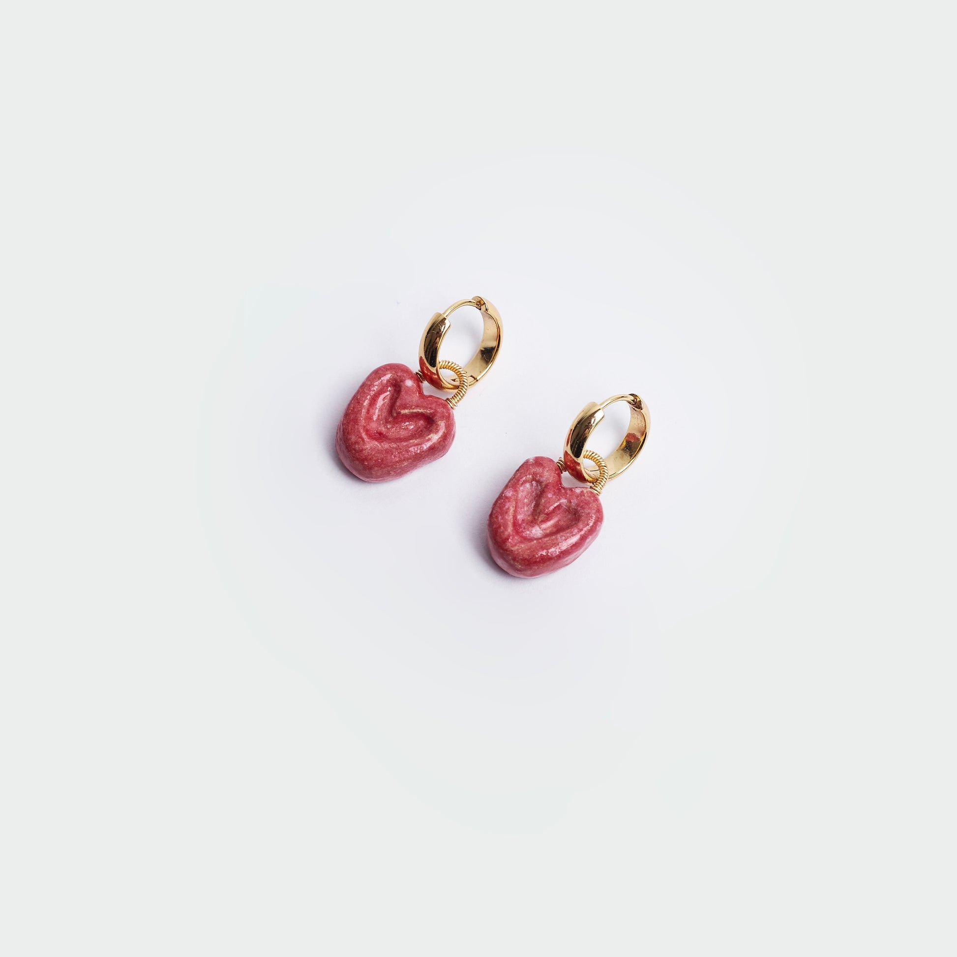 Aretes colgantes estilo hoops en fondo blanco y forma de corazón en color rojo y en material de cerámica con candongas en acero inoxidable en color dorado