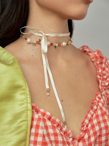 Modelo de tes blanca y cabello negro, con vestido de cuadros rojos y blancos y el chocker Broken Laces con cintilla en color crema de Chouette.
