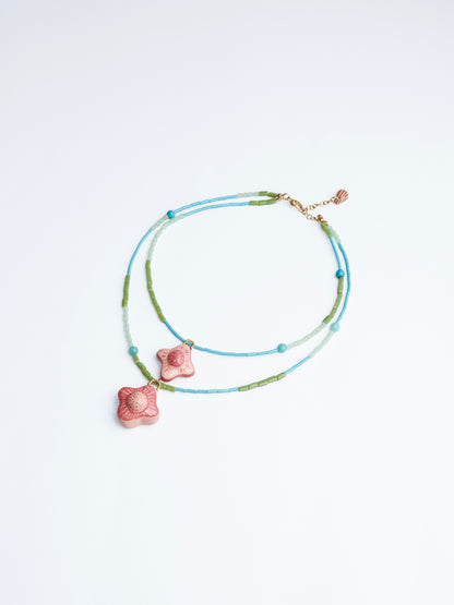 Imagen en fondo blanco de collar doble estilo cascada con doble dije de cerámica con cuencas y cilindros en color azul, turquesa, verde y agua marina de la marca Chouette