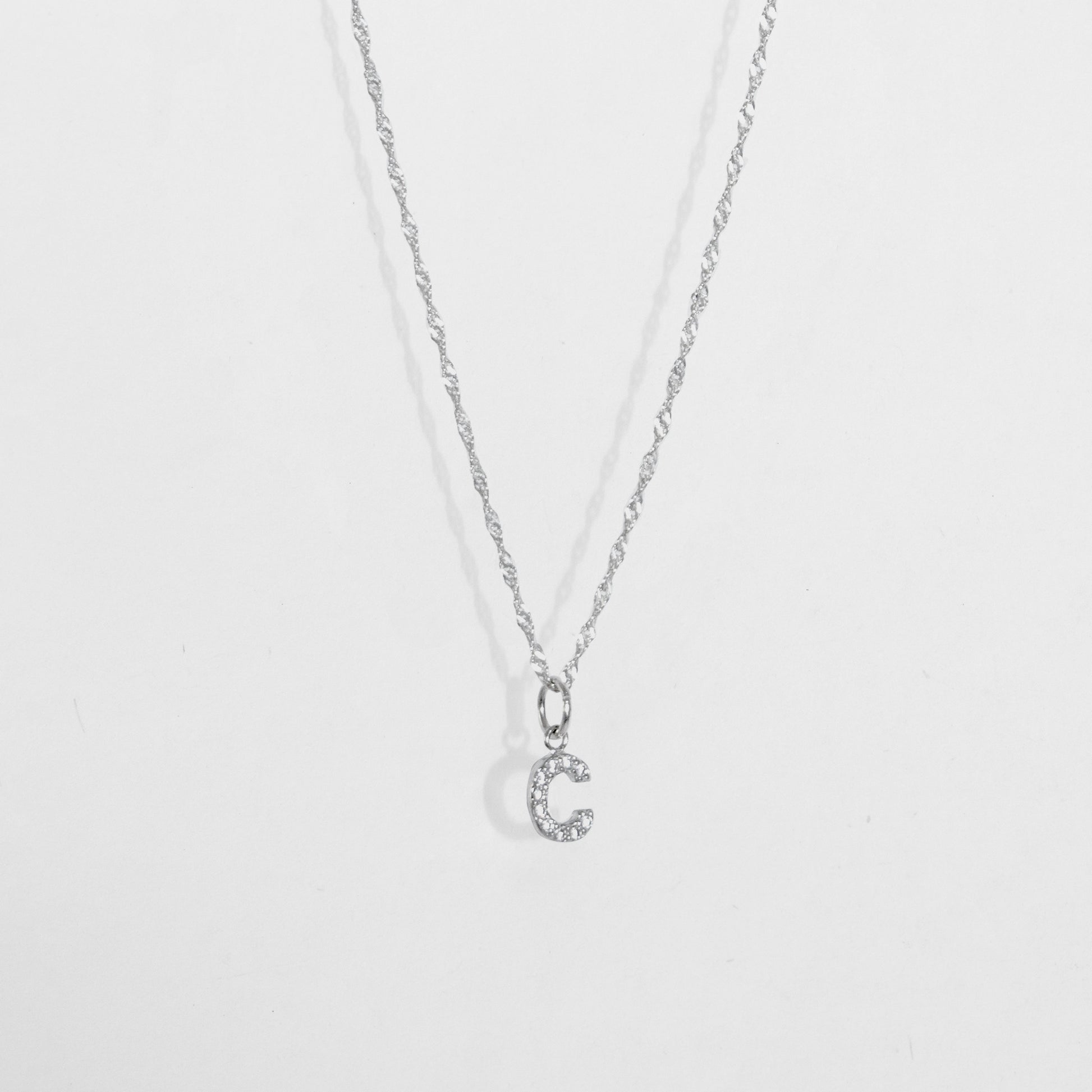 Cadena en material de plata ley 925 en tejido eslabón fino con dije de letra C con diamantes zircones incrustados.