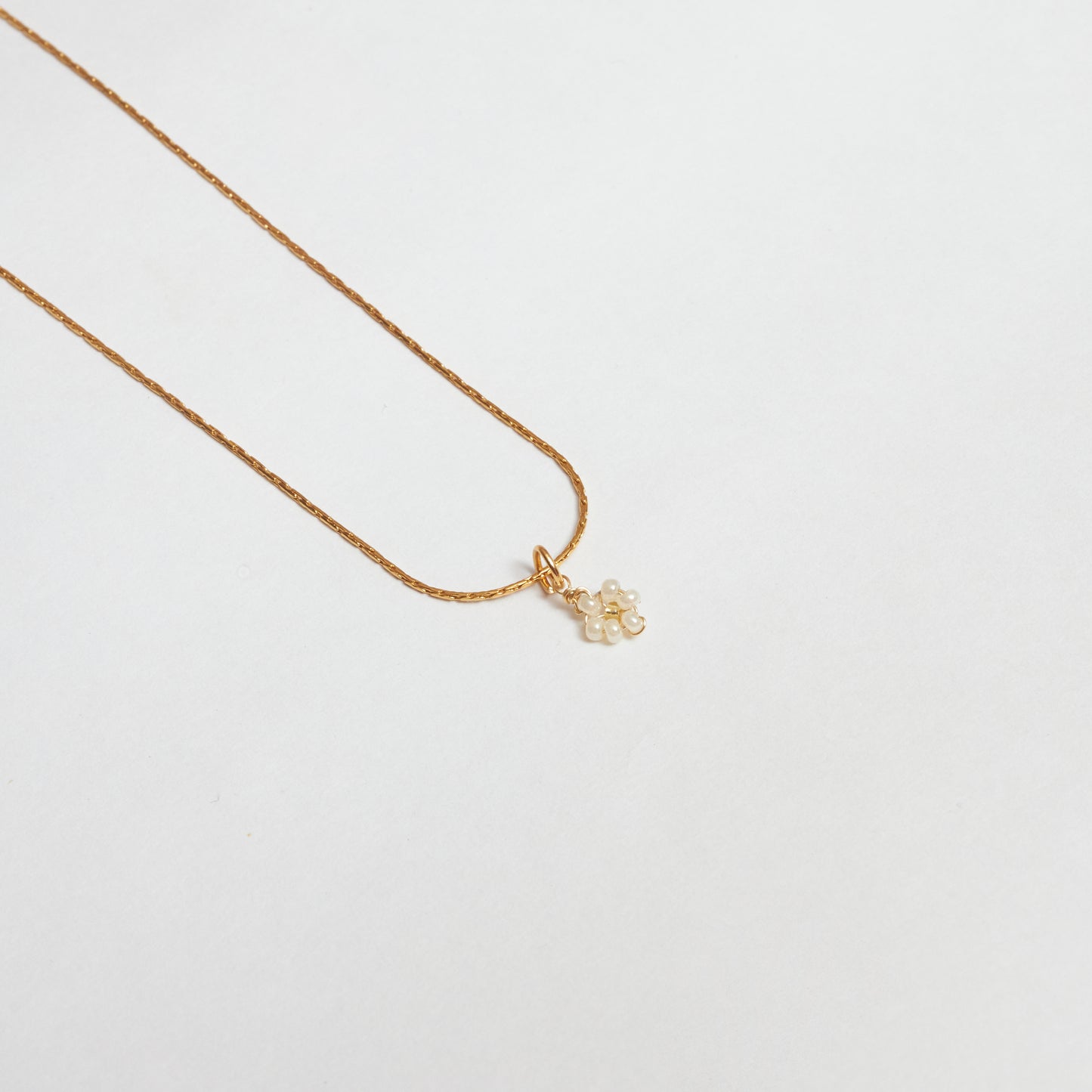 Cadena en material de acero inoxidable en tejido cola de ratón color dorado con dije colgante, tejido a mano en mostacilla con forma de flor color blanco
