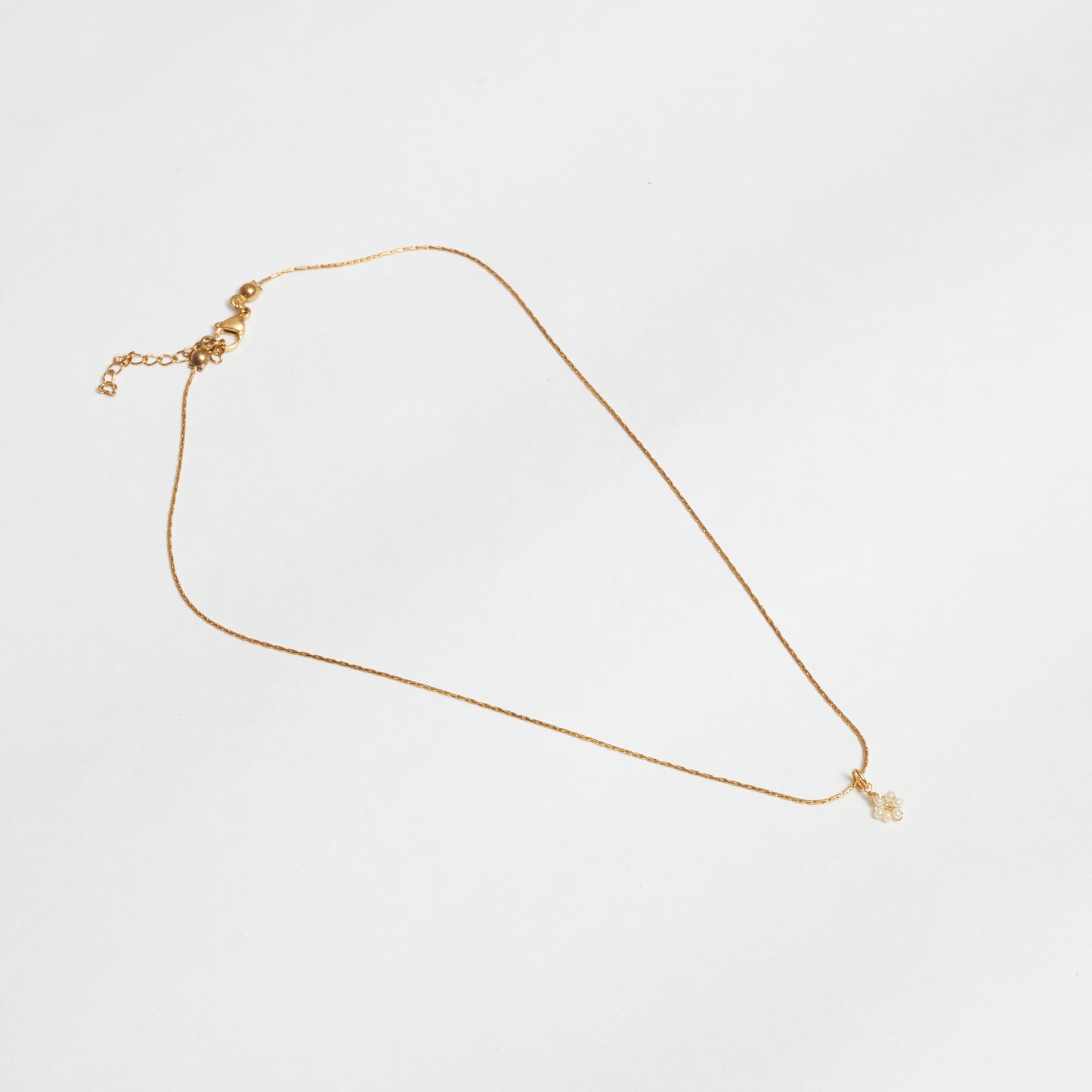 Cadena en material de acero inoxidable en tejido cola de ratón color dorado con dije colgante tejido a mano en mostacilla con forma de flor, color rosado.
