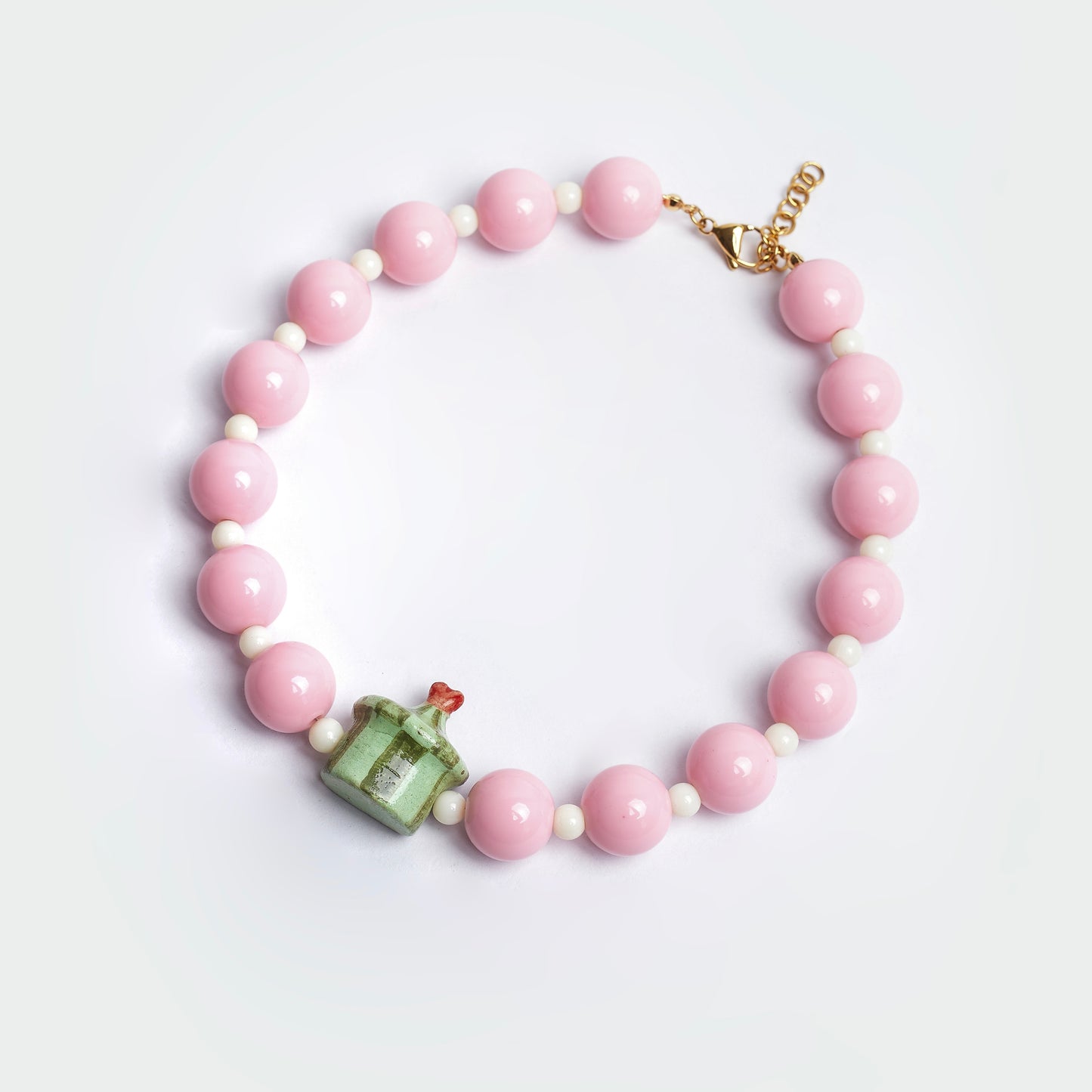 Collar Dulcerp Cidra estilo chunky hecho a mano con perlas color rosa y blanco y un dije en forma de dulcero con punta de corazón en colores verde claro, verde oscuro y rojo en material de cerámica 