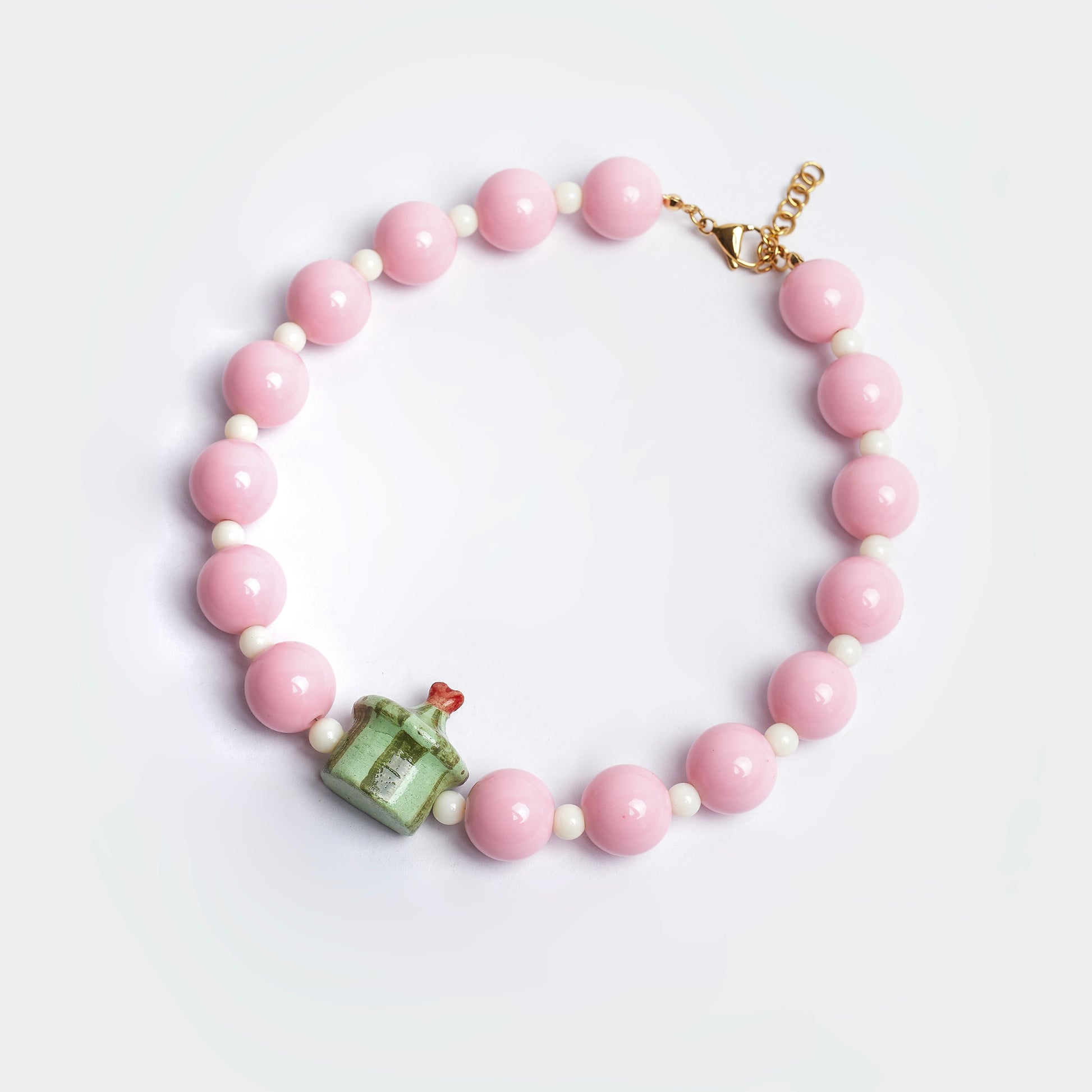 Collar Dulcerp Cidra estilo chunky hecho a mano con perlas color rosa y blanco y un dije en forma de dulcero con punta de corazón en colores verde claro, verde oscuro y rojo en material de cerámica 