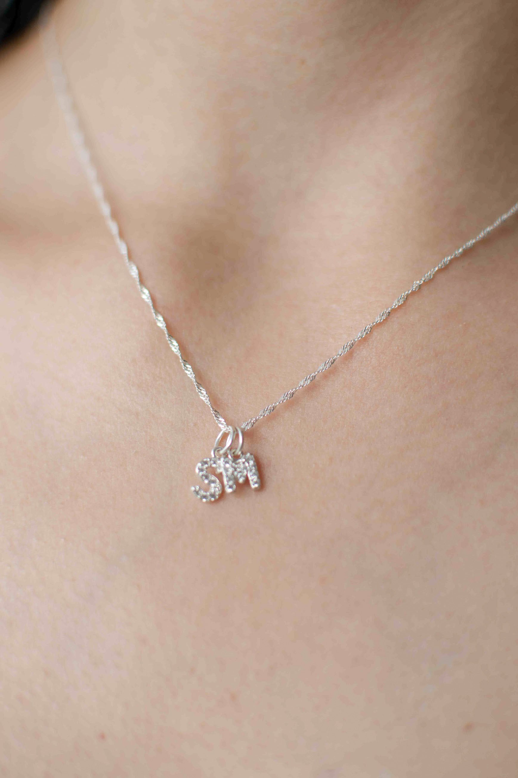Cuello de modelo con cadena clásica de plata ley 925 en tejido de eslabón con dos dijes colgantes de letras S y M