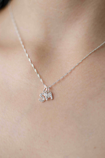 Cuello de modelo con cadena clásica de plata ley 925 en tejido de eslabón con dos dijes colgantes de letras S y M
