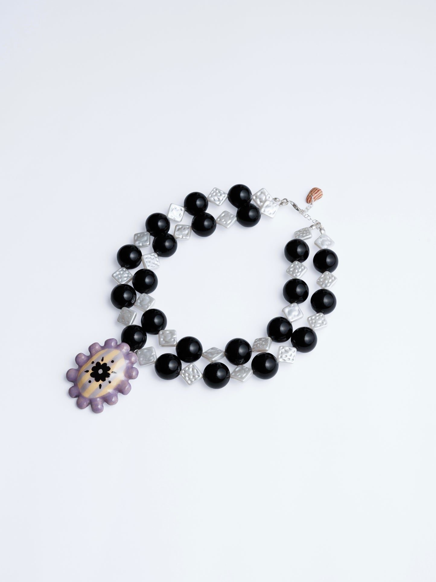 Imagen en fondo blanco de collar medallón sourvenr de chouette en colores blanco, negro, lila, mantequilla y morado.