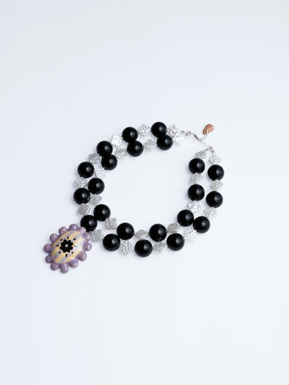 Imagen en fondo blanco de collar medallón sourvenr de chouette en colores blanco, negro, lila, mantequilla y morado.
