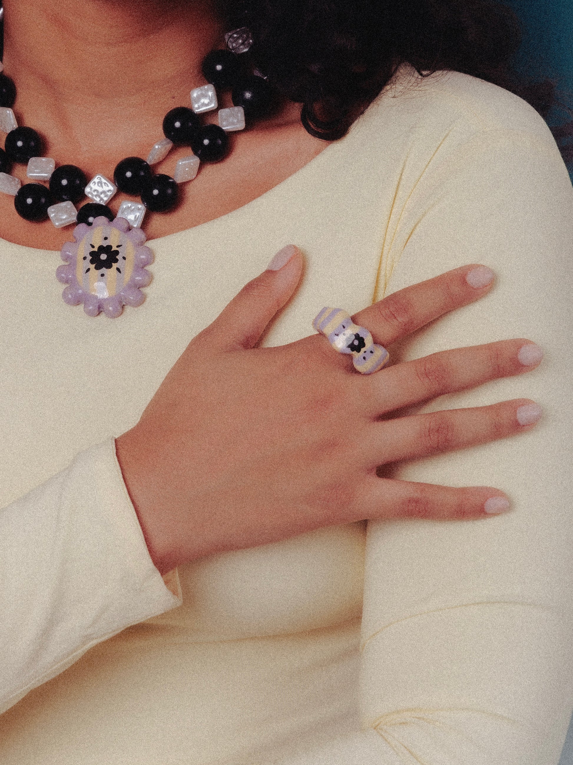 Modelo de tés morena con vestido color mantequilla utilizando el collar Medallón y anillo Sourvenir de Chouette