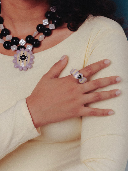 Modelo de tés morena con vestido color mantequilla utilizando el collar Medallón y anillo Sourvenir de Chouette