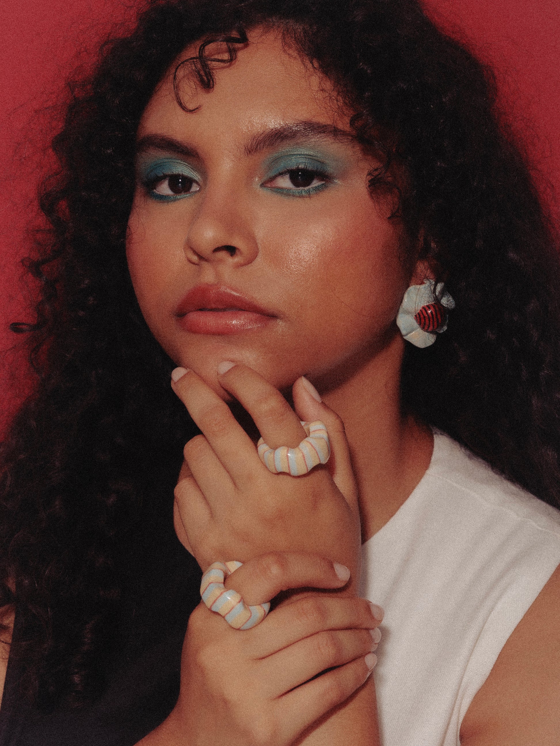 Imagen de modelo de tés morena y cabello ondulado, utilizando un vestido blanco y negro y anillos turquesa y earrings heirloom de Chouette