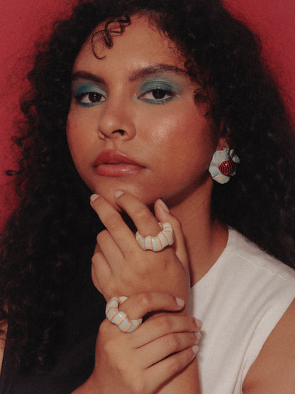 Imagen de modelo de tés morena y cabello ondulado, utilizando un vestido blanco y negro y anillos turquesa y earrings heirloom de Chouette