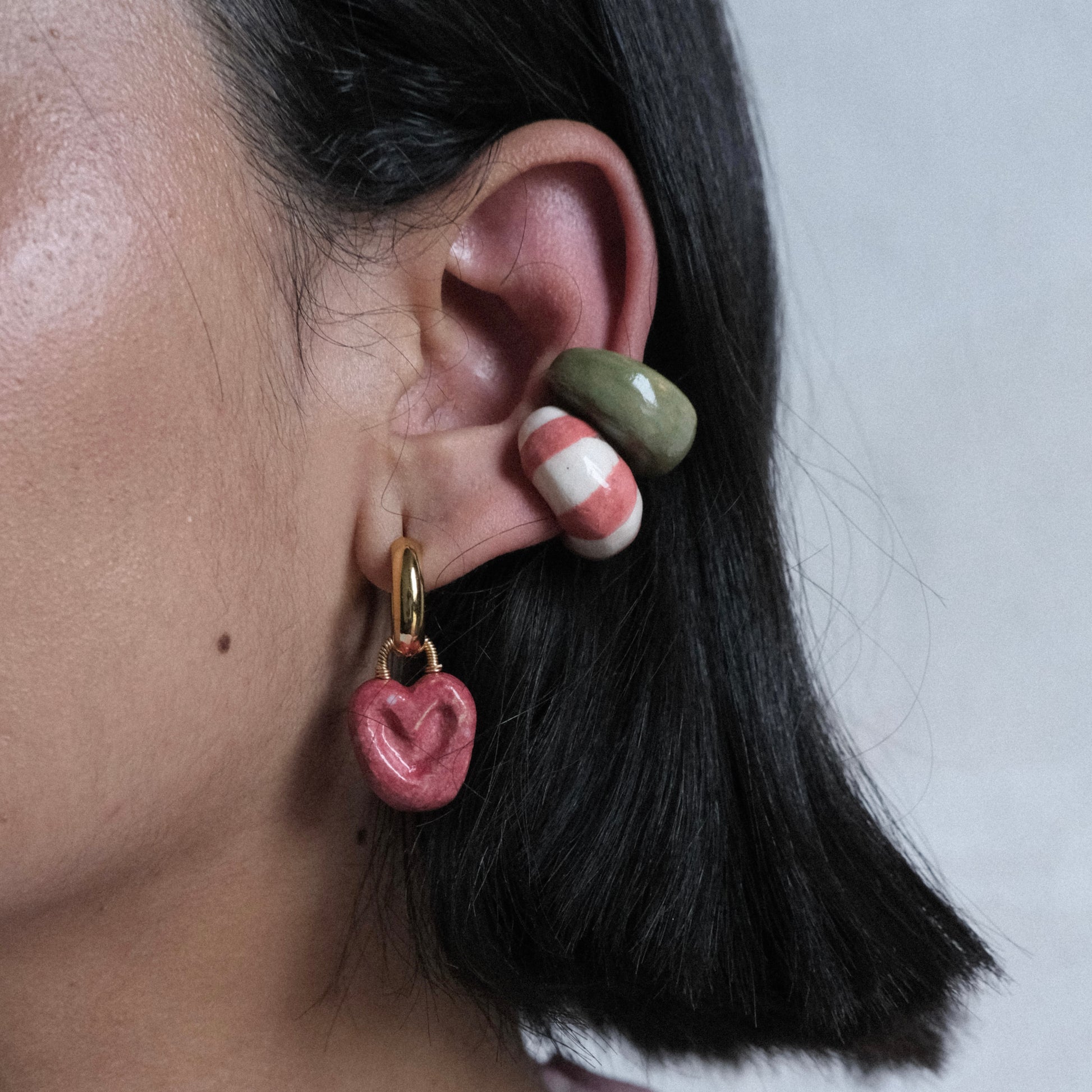 Perfil izquierdo de modelo de tes morena con cabello corto de color negro con set Bombón de Chouette que incluye dos earcuff, uno clasico y otro festival y Hoops Manjar Bocadillo