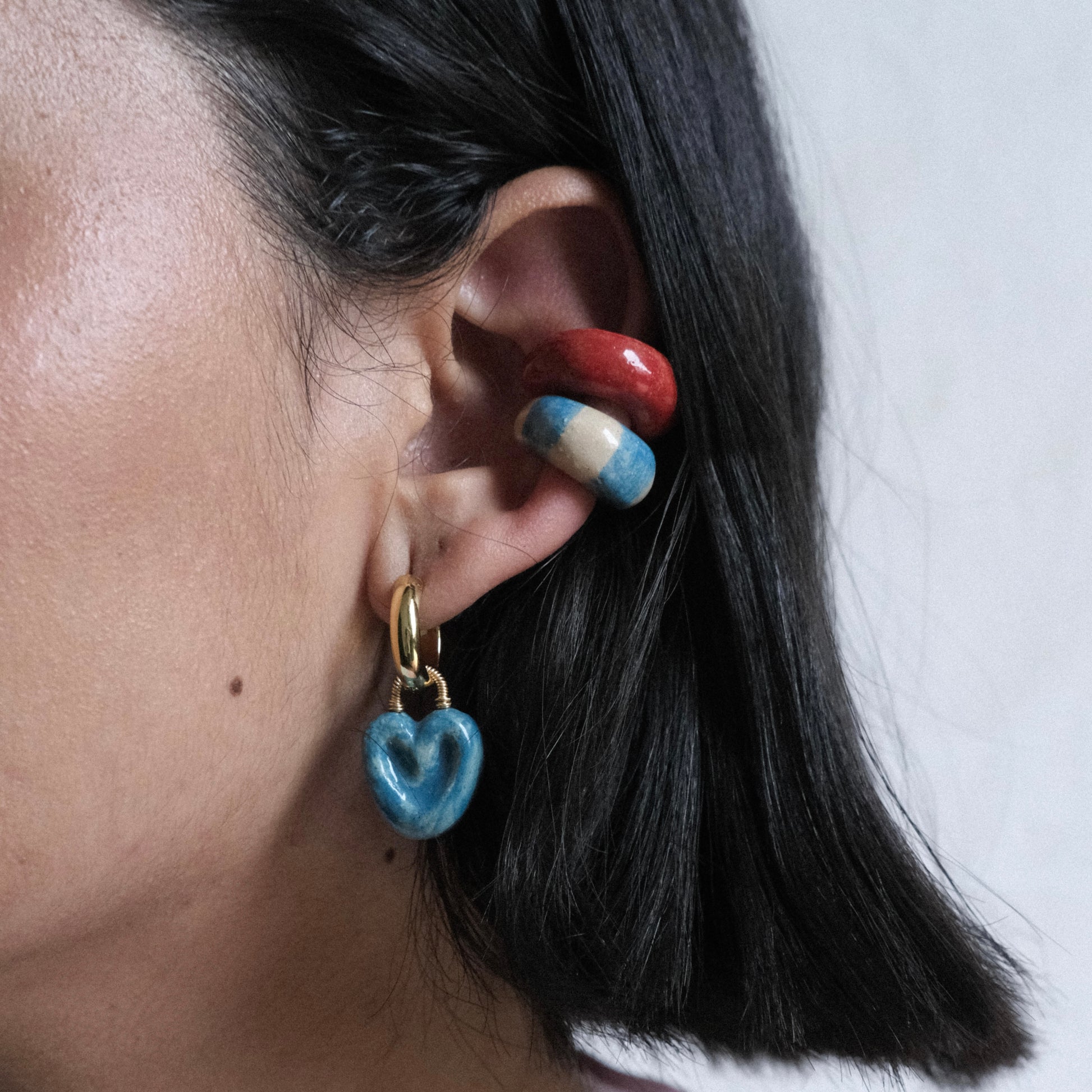 Perfil izquierdo de modelo de tes morena y cabello corto color negro, usando el set Bombón de Chouette que incluye dos Earcuff clásico o festival y hoops Manjar Mora Azul o Bocadillo