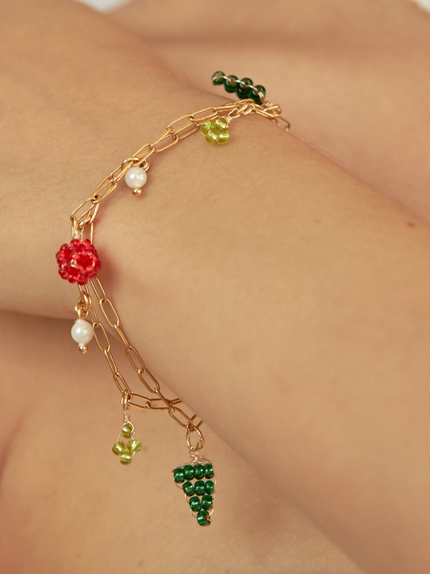 Brazo de modelo de tes blanca con brazalete the bouquet con doble cadena y dijes tejidos.