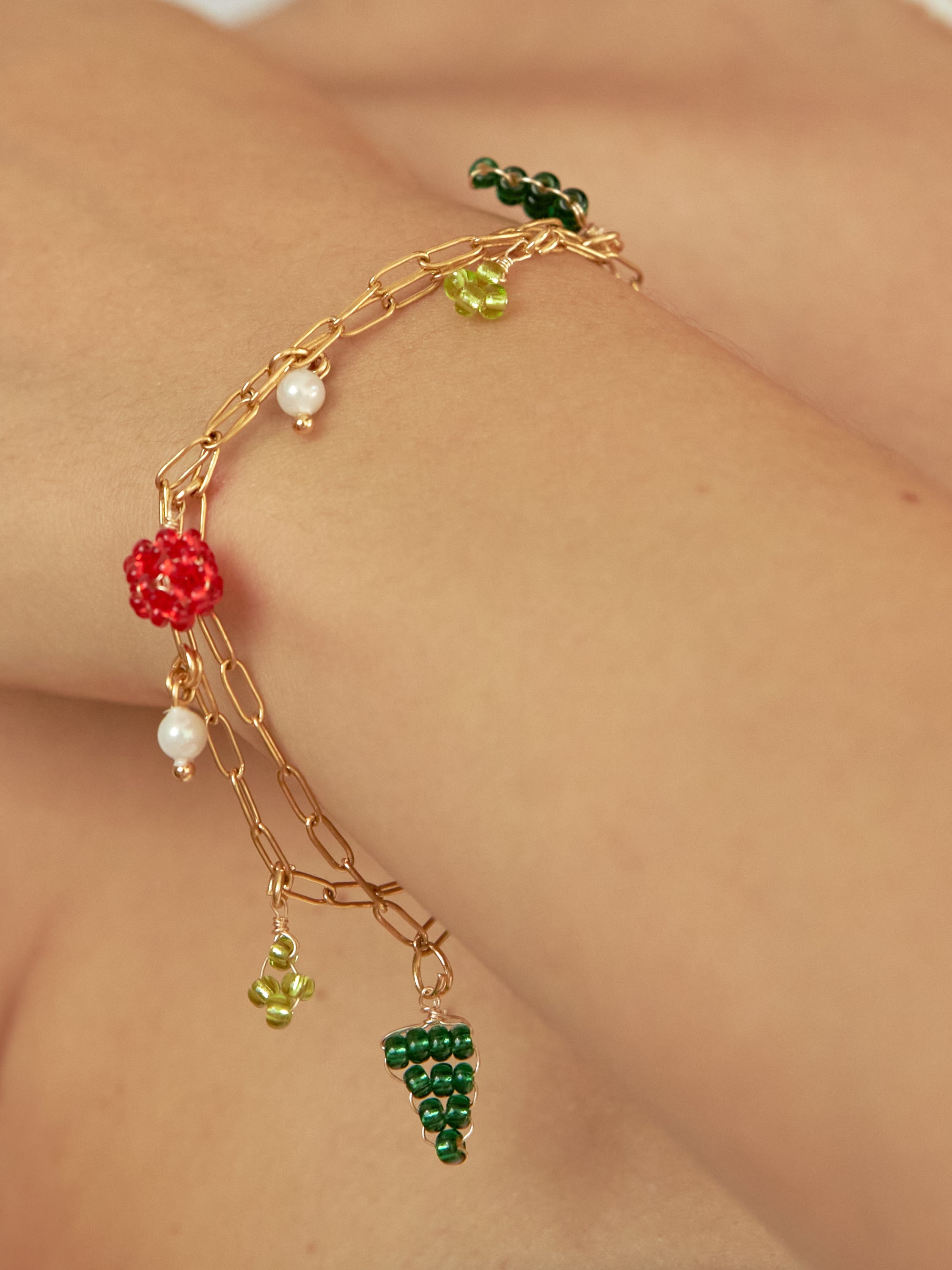 Brazo de modelo de tes blanca con brazalete the bouquet con doble cadena y dijes tejidos.