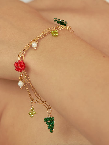 Brazo de modelo de tes blanca con brazalete the bouquet con doble cadena y dijes tejidos.