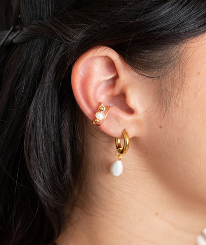 oreja de modelo de tes blanca con cabello negro con earcuff Seulement tejido en alambre con múranos y candongas con dije de perla colgante.

