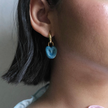 Perfil derecho de modelo de tes morena y cabello corto color negro, usando Hoops Manjar Mora Azul