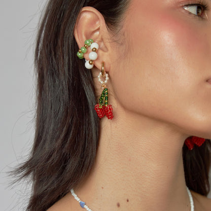 Modelo de tes blanca y cabello negro con candonga en acero color dorado y dije de cereza.